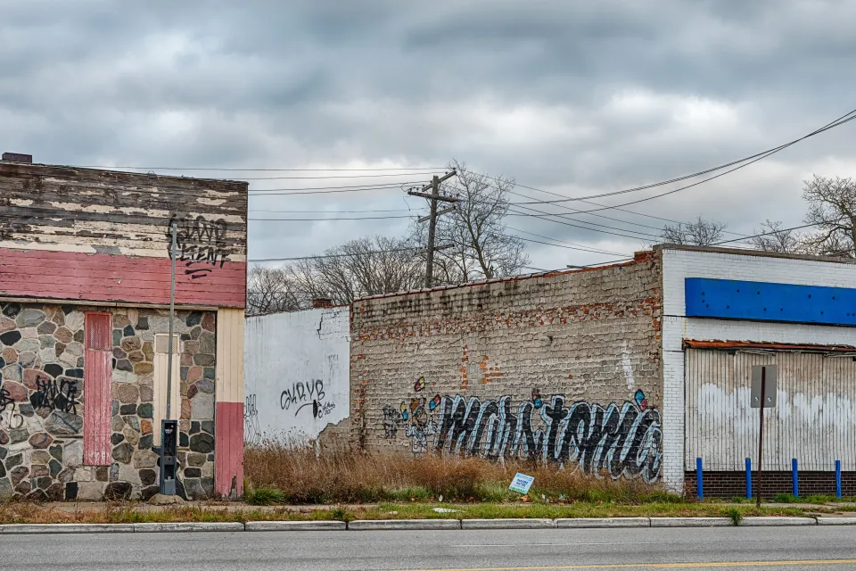 A vacant lot between two one-story brick buildings with graffiti in Detroit, Michigan